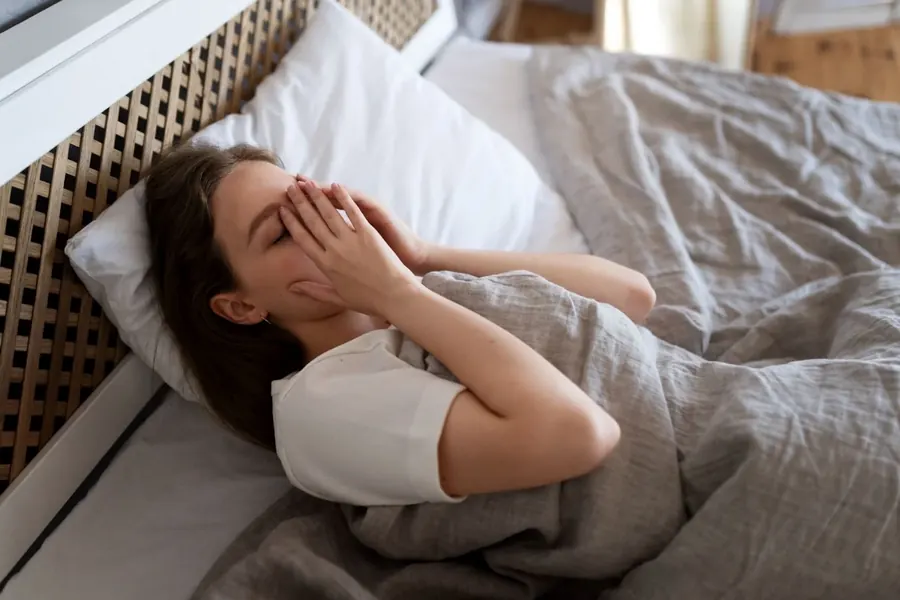A woman waking up exhausted after a short night’s sleep.