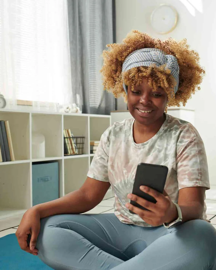 Woman sitting on a yoga mat checking LifeLeaf Coach on her phone