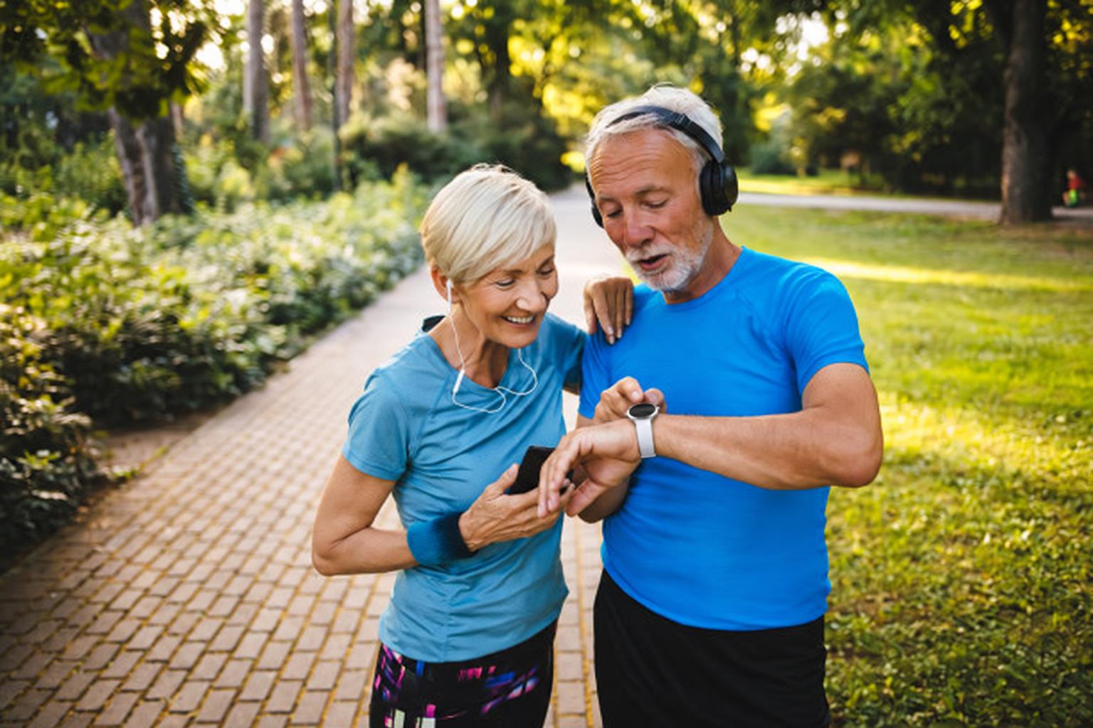 An older couple outdoors, checking a LifeLeaf on a morning walk.