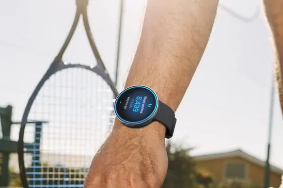 A tennis player wearing LifeLeaf, picking up a ball.