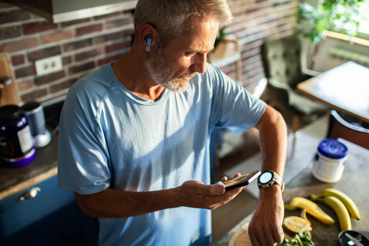 A man in his kitchen checking the LifeLeaf app beside the food he is preparing.